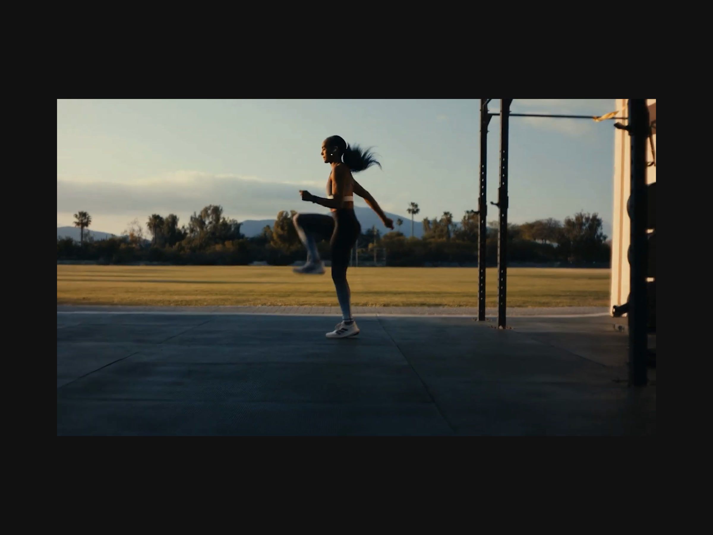 A runner doing high knees at sunset, from the activewear campaign video.
