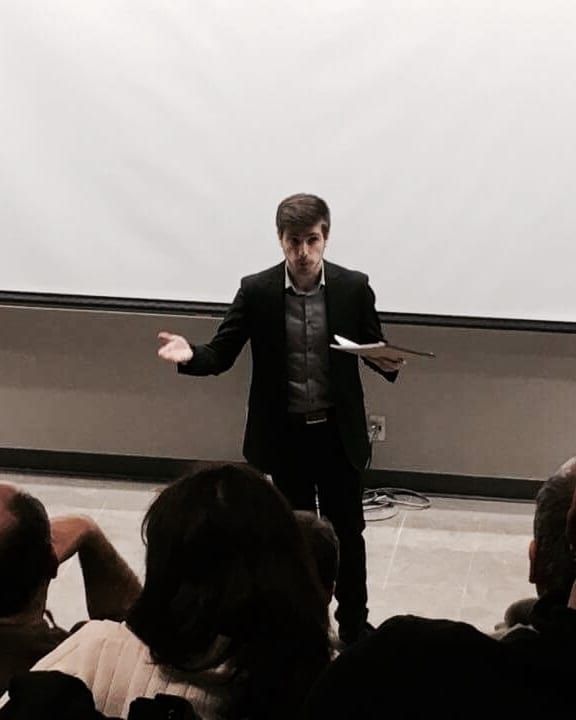 Araik presenting to a seated audience in a lecture hall.